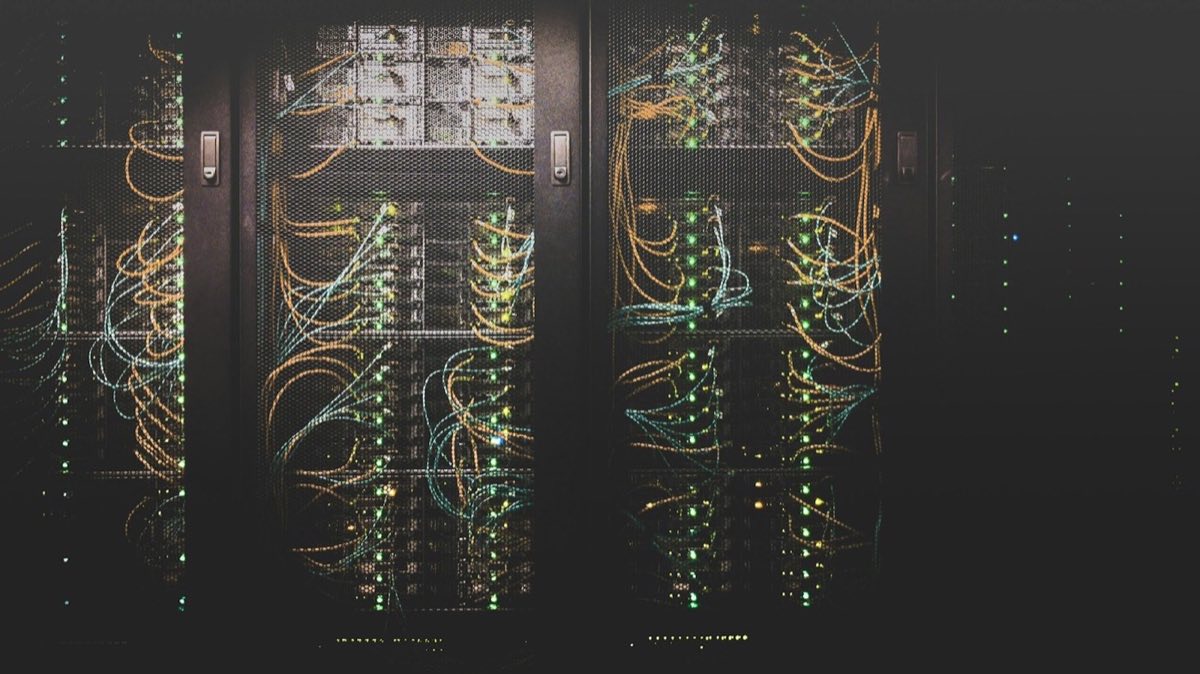Rows of server racks in a data centre with patch cables running between them
