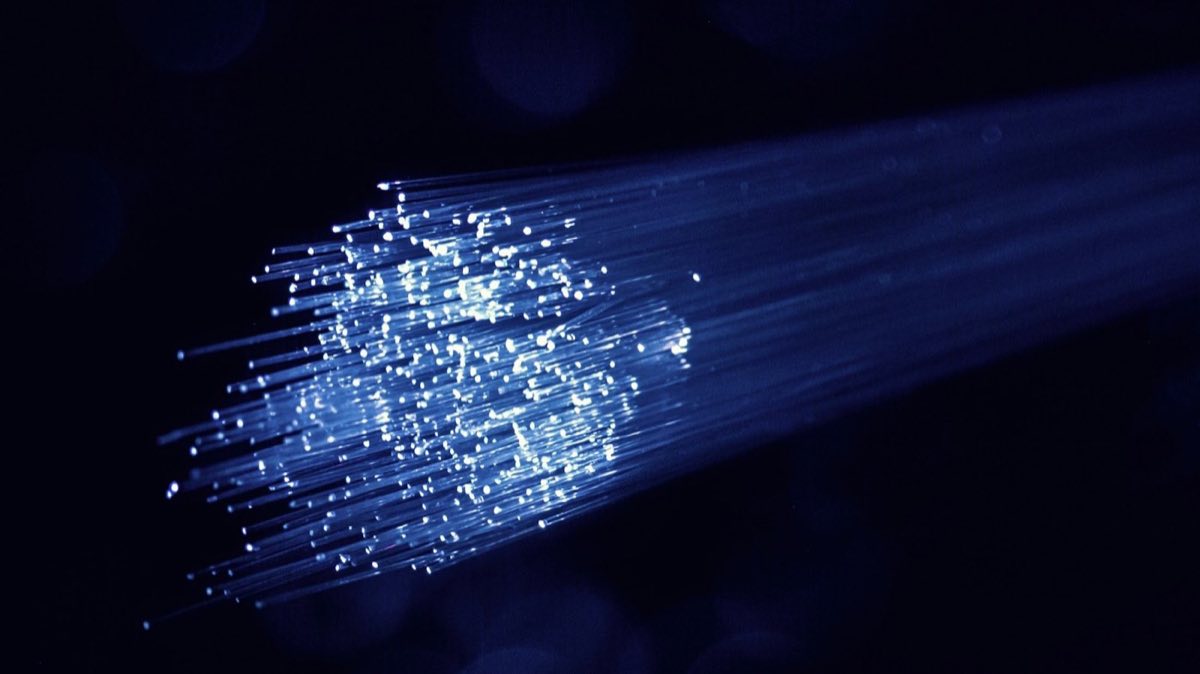A bundle of fibre optic strands carrying blue light in a dark room