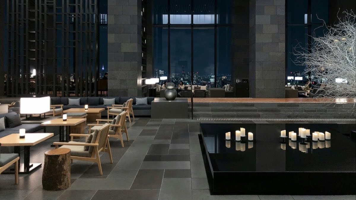 The lounge area of a modern hotel with tables and low lighting