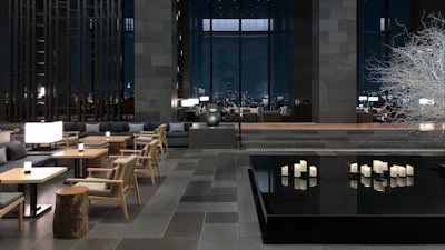 The lounge area of a modern hotel with tables and low lighting
